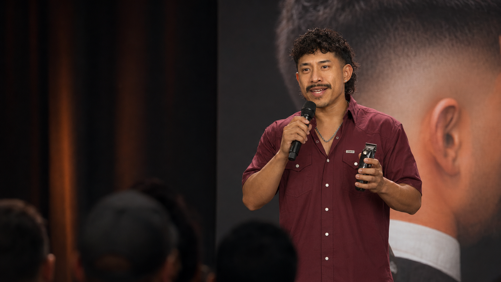 Jorge teaching on stage with a microphone and clippers