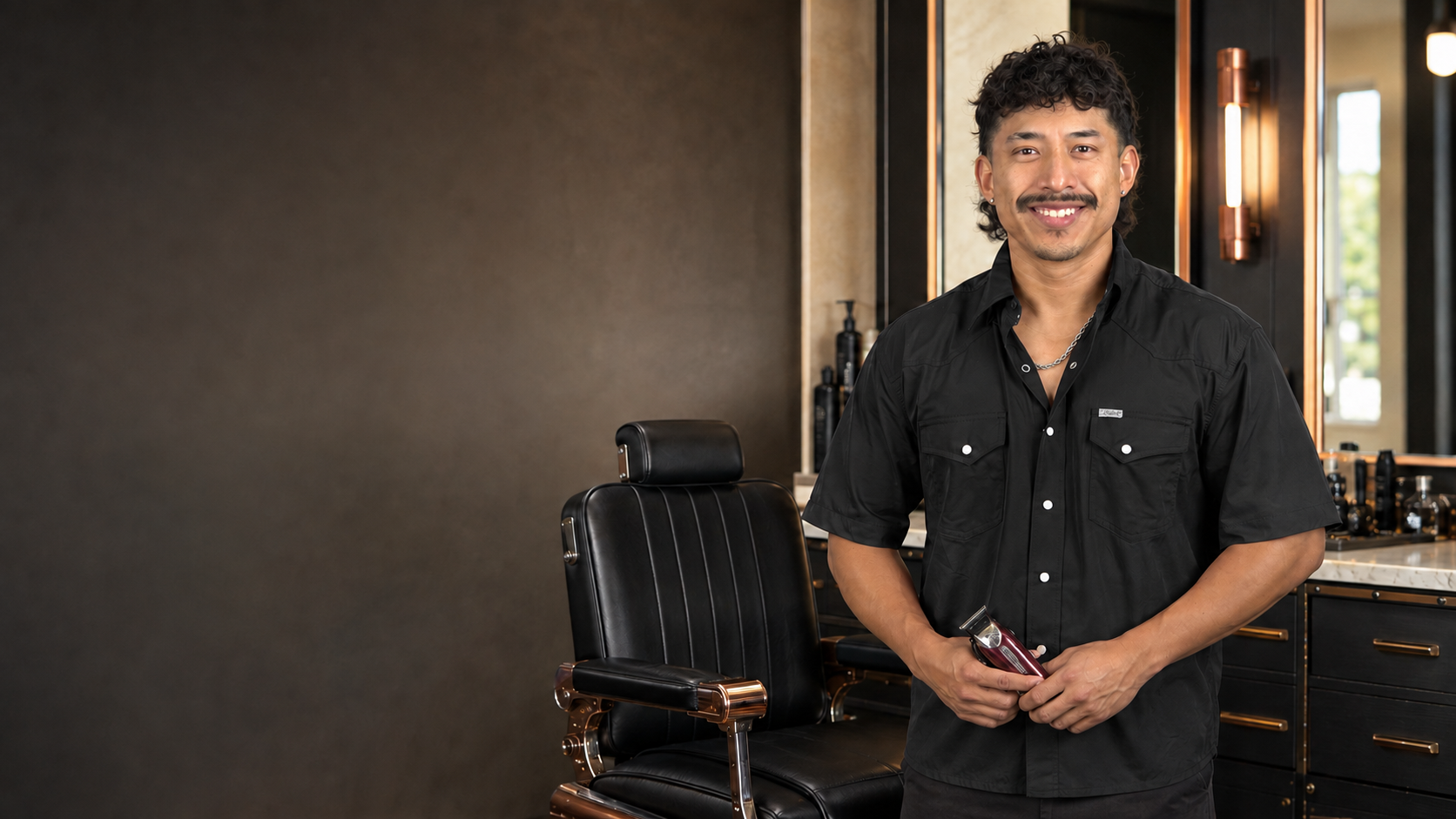 Jorge standing beside his barber chair, clippers in hand